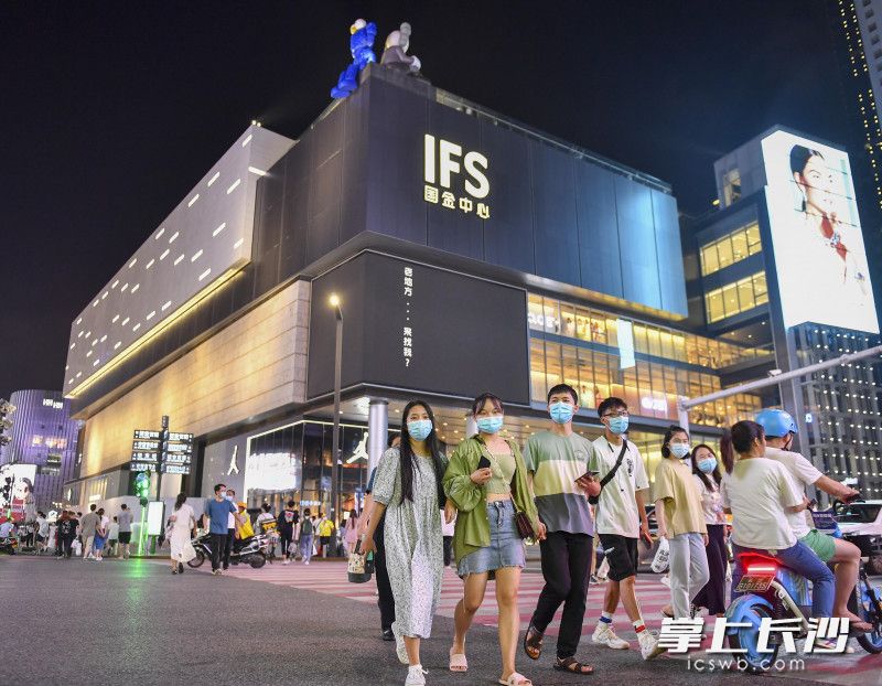 市民、游客佩戴口罩在长沙国金中心前游玩。
