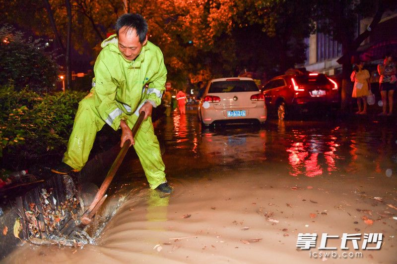 8月18日晚，银杉路谷岳路口，岳麓市政工作人员正在清理排水口的垃圾加大排水。