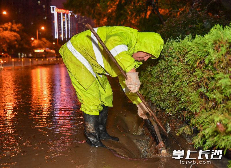 8月18日晚，银杉路谷岳路口，岳麓市政工作人员正在清理排水口的垃圾加大排水。