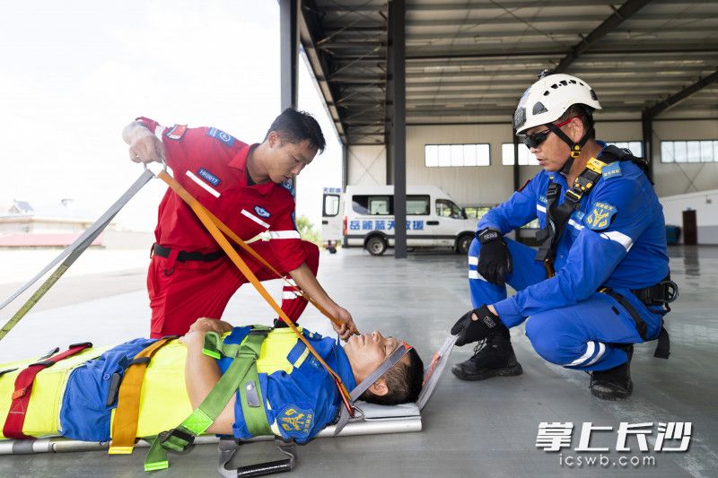 绞车手教授伤员转移技巧，队员张寒被固定在直升机救援担架上。