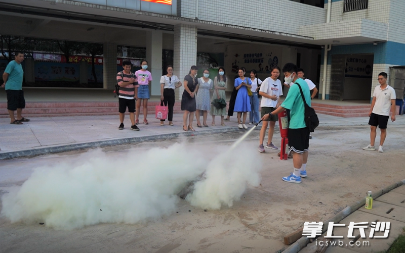 消防指战员讲解灭火器的使用方法，老师们进行实操。均为长沙晚报通讯员 冯运文 供图