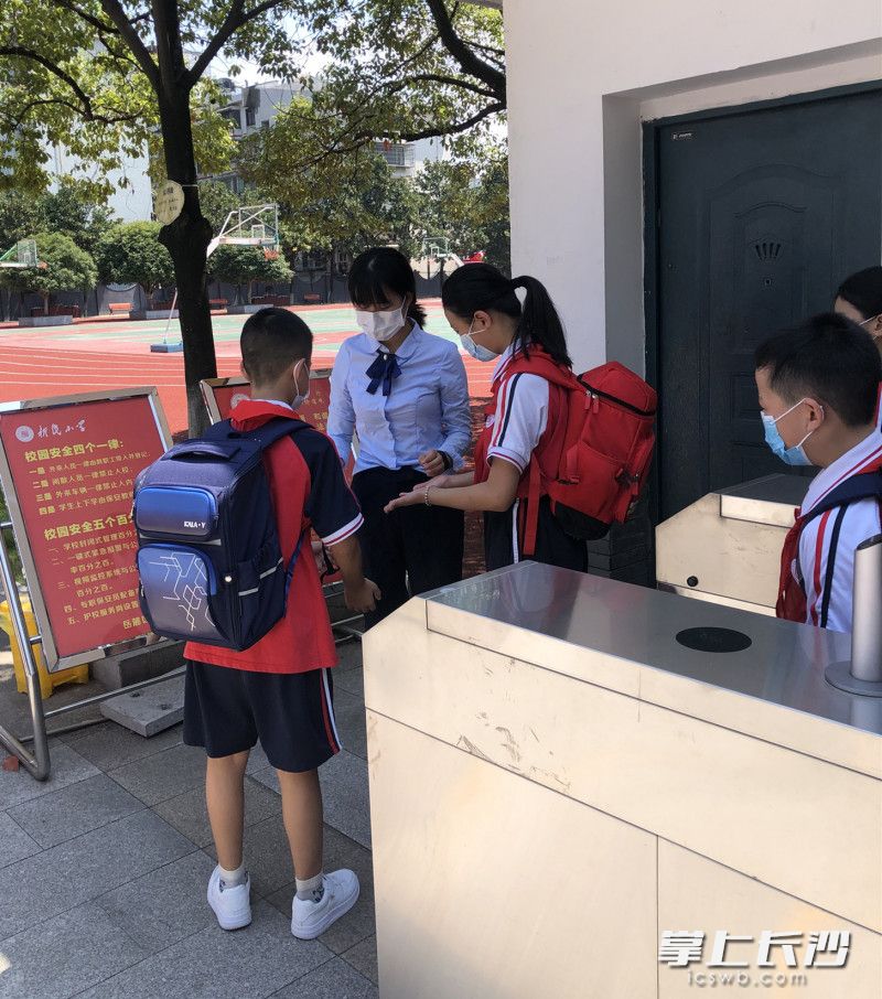 岳麓区新民小学师生佩戴口罩，经过测温和消毒后有序进入校园。通讯员 高文明 供图