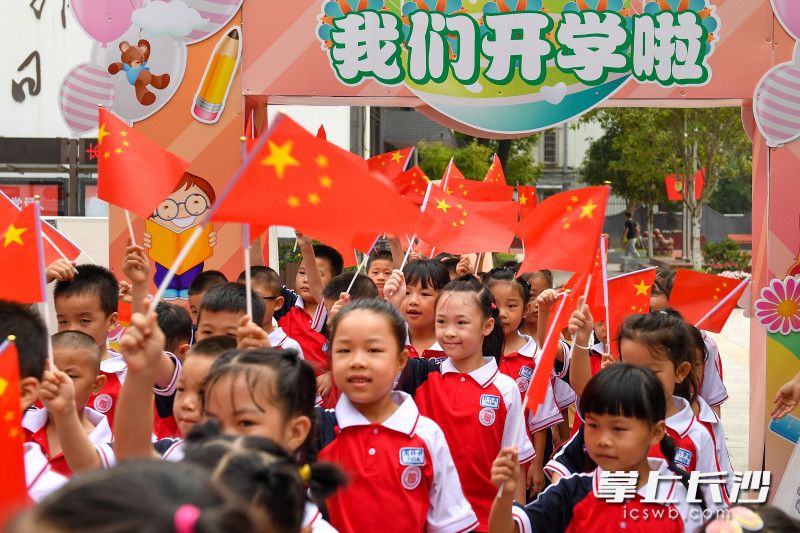 一年级新生挥舞着红旗，兴奋地走出校门。