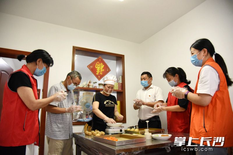 9月15日，“长沙好人”叶宗武、段辉群（左三）夫妻和孙家闯（右三）在“段妈妈烘焙坊”与志愿者一道，为社区困难群众做月饼。  均为长沙晚报全媒体记者刘琦摄