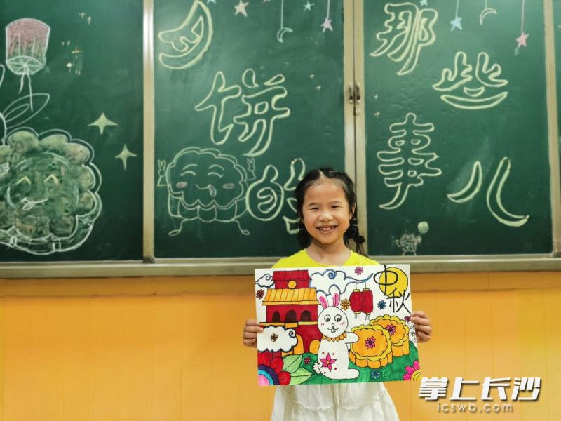 二年级的叶新汝同学在展示她的画作《玉兔与月饼》。学校供图
