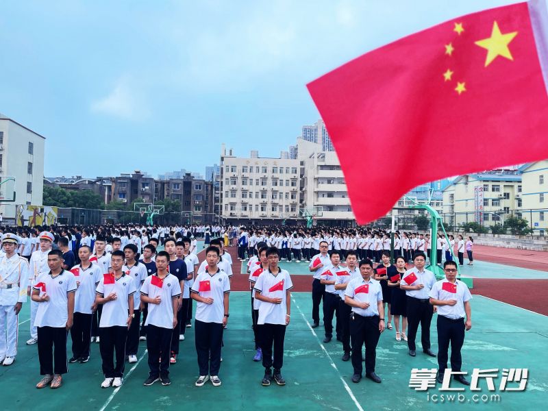 9月27日，长沙市周南雨花中学师生手持国旗，注视着五星红旗冉冉升起，用庄重的仪式表达拳拳爱国之心。