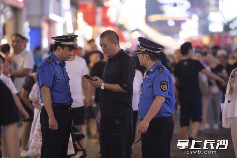 巡查值守以外，城管执法队员们还不时为游客解答问题。
