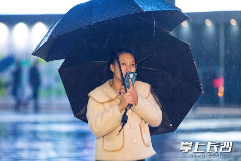 一位女子撑起了两把雨伞，一把遮风，一把避雨。