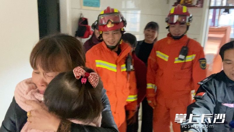 消防员将门打开后，奶奶一把抱起孙女。均为视频截图