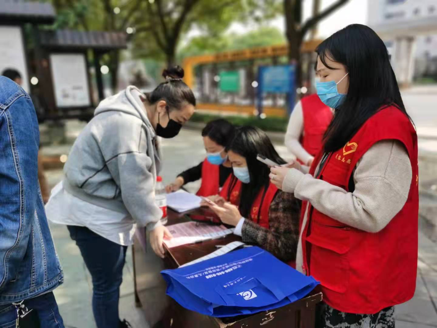 在核酸检测站旁，志愿者指导帮助市民填写相关信息。