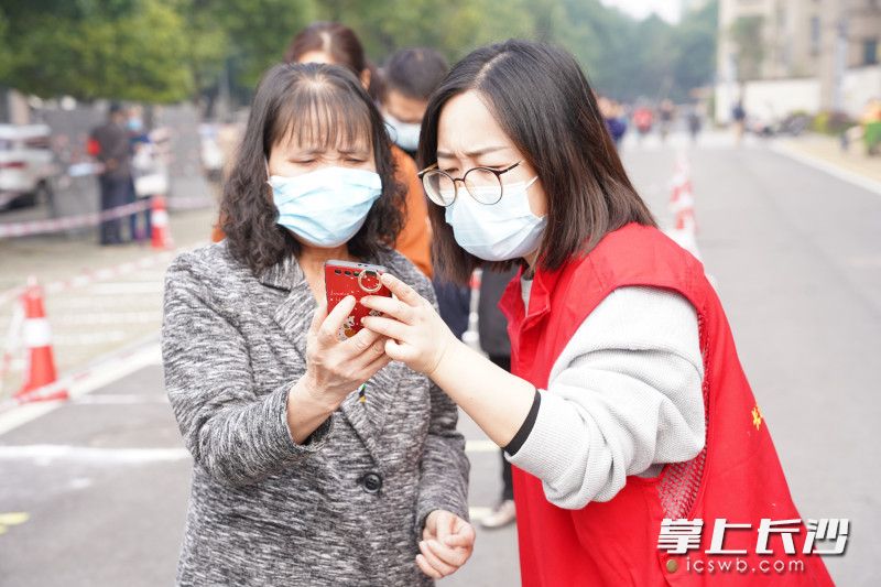 社区工作者教老年居民验证健康码入场。 通讯员 李建兵 摄