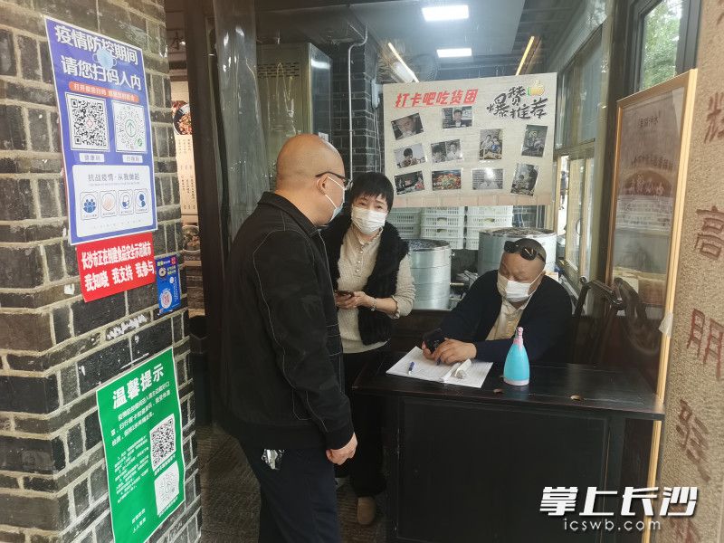 防控人员对白沙井社区商家进行排查。