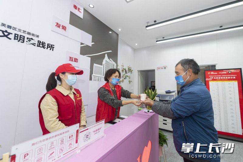 雷锋志愿者服务站的志愿者给前来咨询的市民递上一杯水。   长沙晚报全媒体记者 郭雨滴 摄