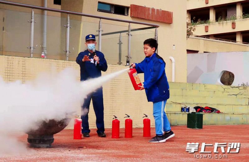 在消防员的指导下，学生使用干粉灭火器成功灭火。