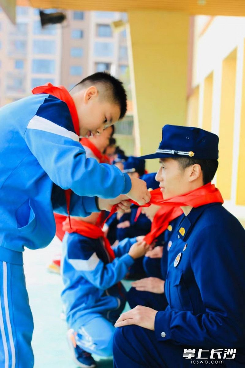 明华小学的学生们为消防员叔叔系上红领巾。