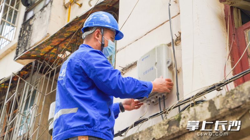 岳光军正在对楼房外盘踞在钢丝绳上的网络线路进行整理约束。