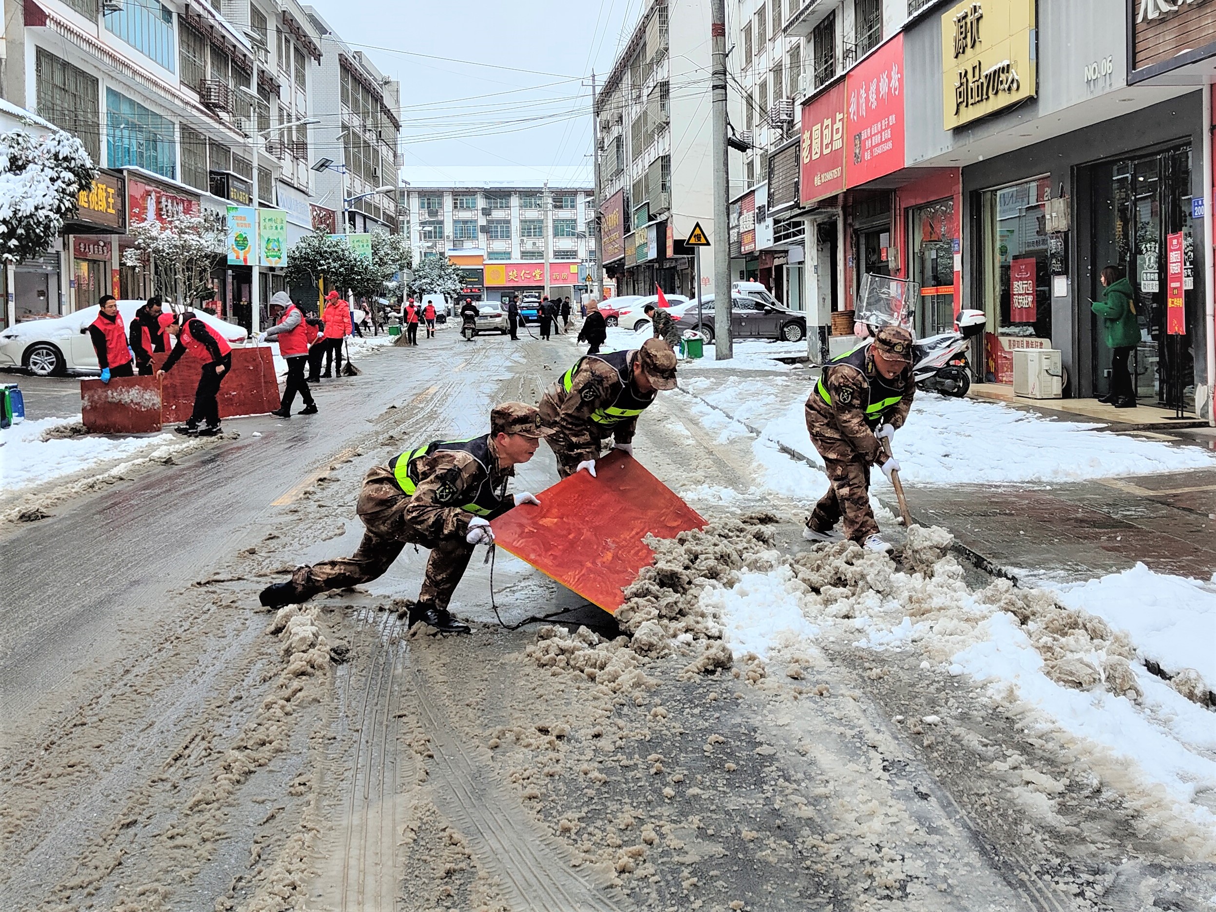 在宁乡市巷子口镇扫雪现场，大伙发明了“扫雪神器”——木制三合板，多人合作铲雪干净，且不会破坏路面。 长沙晚报全媒体记者 张禹 通讯员 李向 邓晨雨 摄影报道