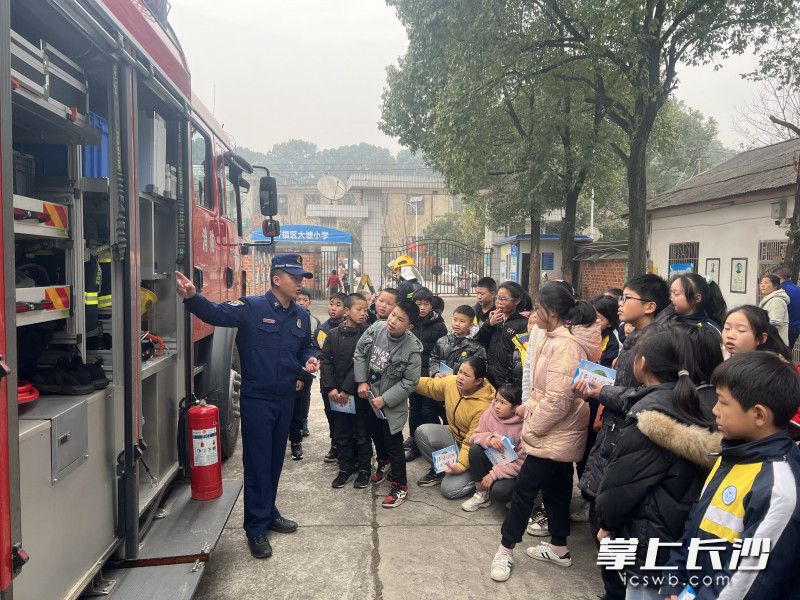 消防宣传人员为同学们介绍消防车上的装备。