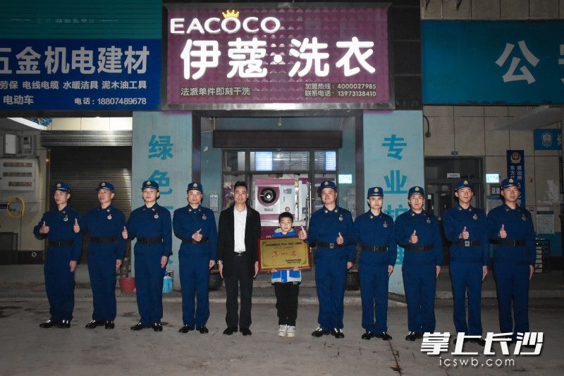 在秦勇忠的洗衣店前，东方红消防救援站消防员特意来与他分享喜悦，合影留念。长沙晚报通讯员 李文翠 供图