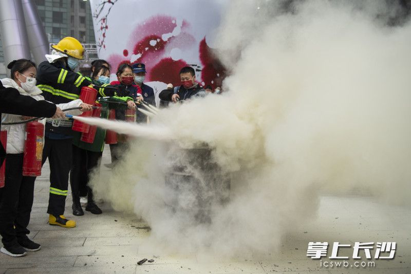 消防员教授商场员工使用干粉灭火器。