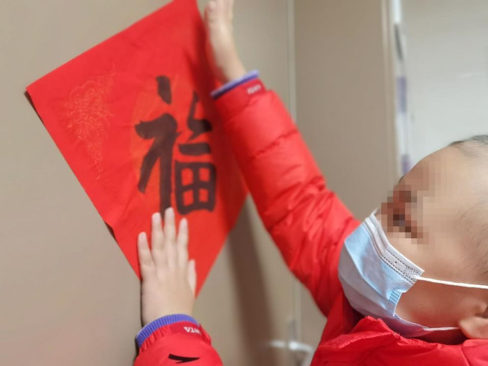 患儿把福字贴在病房门上。