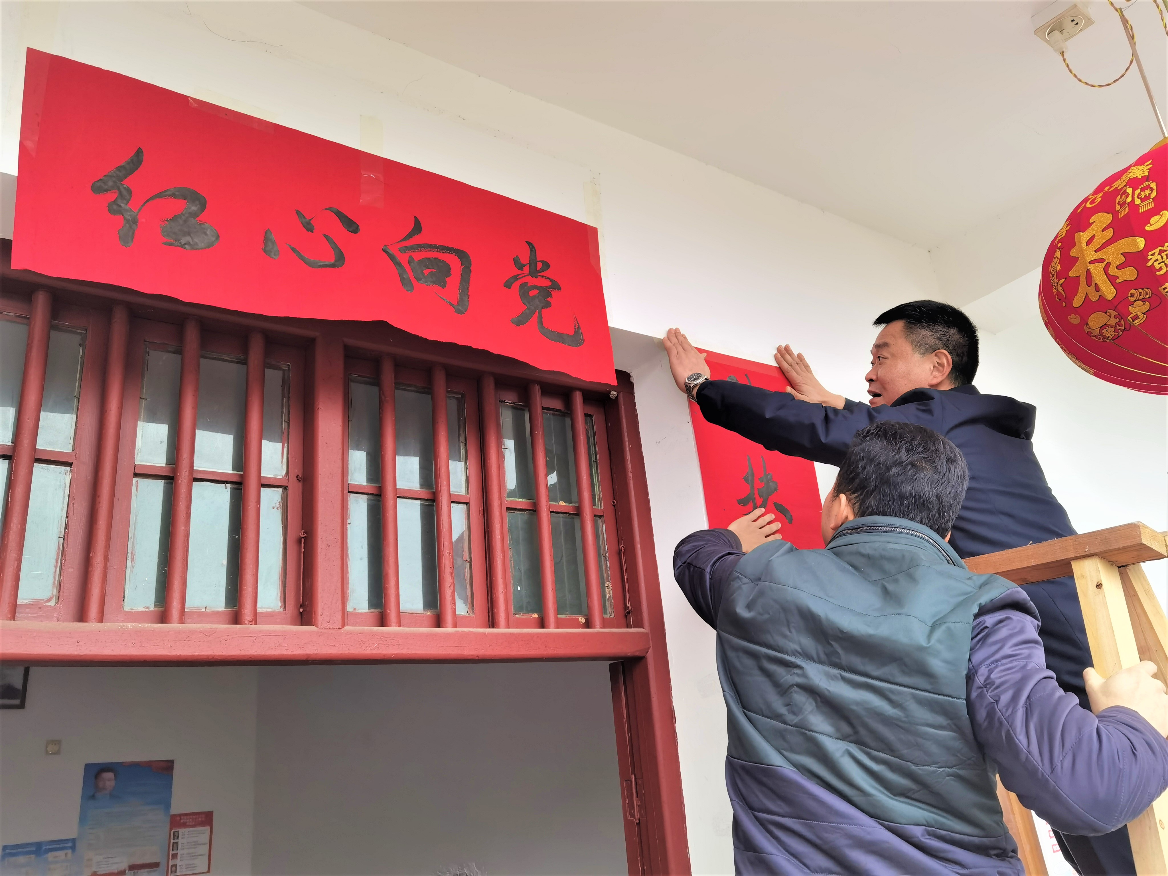 “来来来，咱们一起给蔡老哥家贴春联。”在宁乡市煤炭坝镇双龙村，镇村干部陪脱贫户蔡国庆一家吃小年饭，并一起贴春联。长沙晚报全媒体记者 张禹 摄