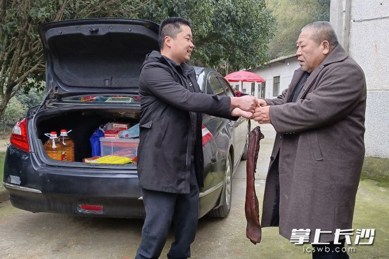汤俊杰（左）将一块腊肉送给独居老人。长沙晚报通讯员 王国光 供图