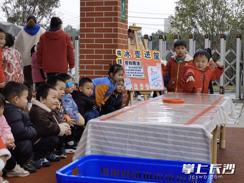 萌娃在玩冰壶进筐游戏。