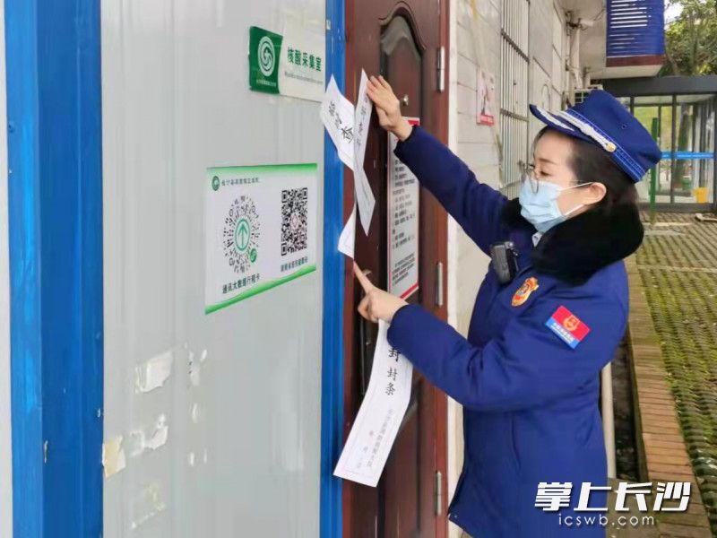 消防监督员对核酸采集室大门处加贴封条。