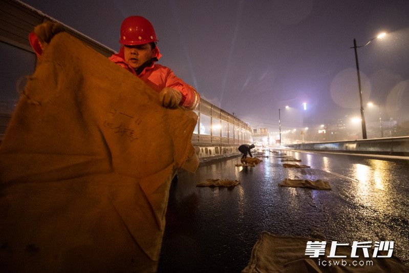 每铺设一个麻袋，工作人员都会细心的将每个折角整理好，以让麻袋贴合路面。