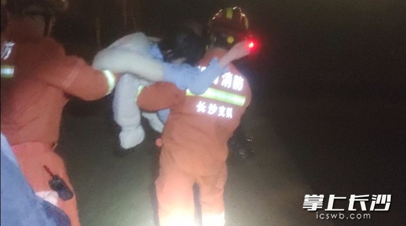 因女子无法行走，消防救援人员抱着她走到安全位置。视频截图