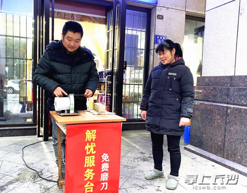 韦文沁在自家小店门前摆出“解忧服务台”，用一技之长为居民免费磨刀、义务维修。长沙晚报全媒体记者  胡媛媛 摄
