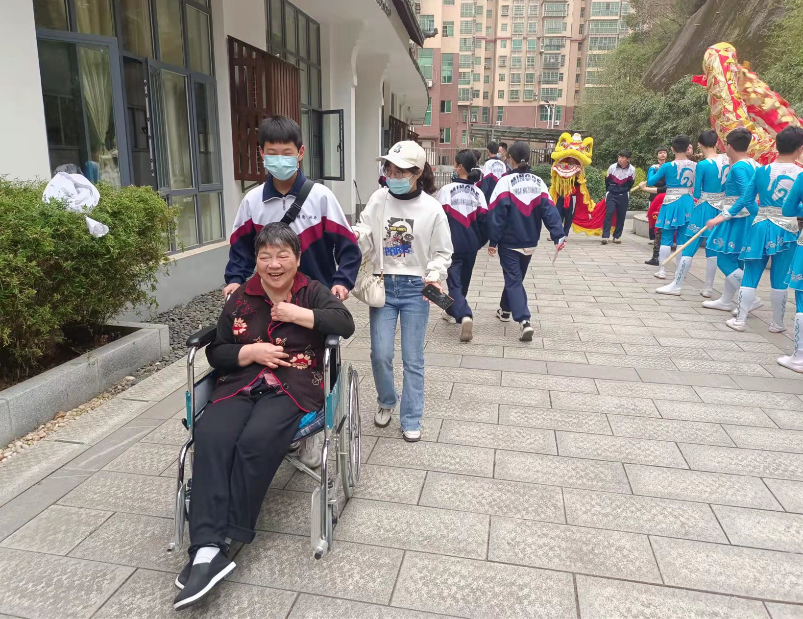一名学生志愿者推着轮椅上的老人去看表演。均为长沙晚报全媒体记者 陈良  通讯员 罗群 摄影报道