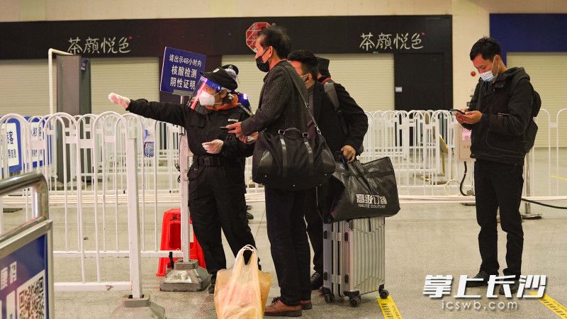 长沙火车南站保安正在引导乘客安全过检。