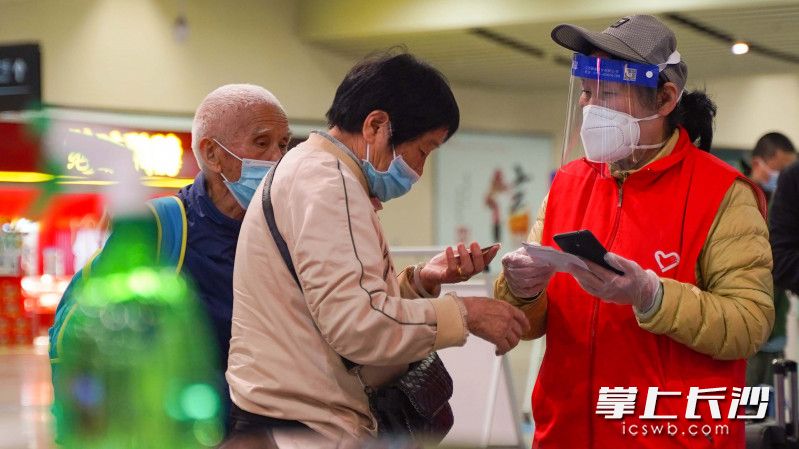 长沙火车南站志愿者正在帮助过往乘客检查健康码和场所码。