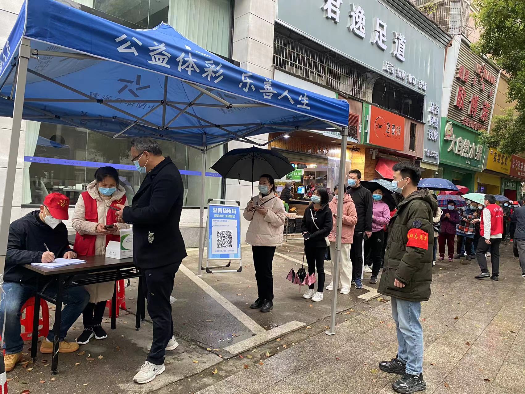 蒋恋峰（右一）正在社区核酸采样点维持秩序。受访单位供图