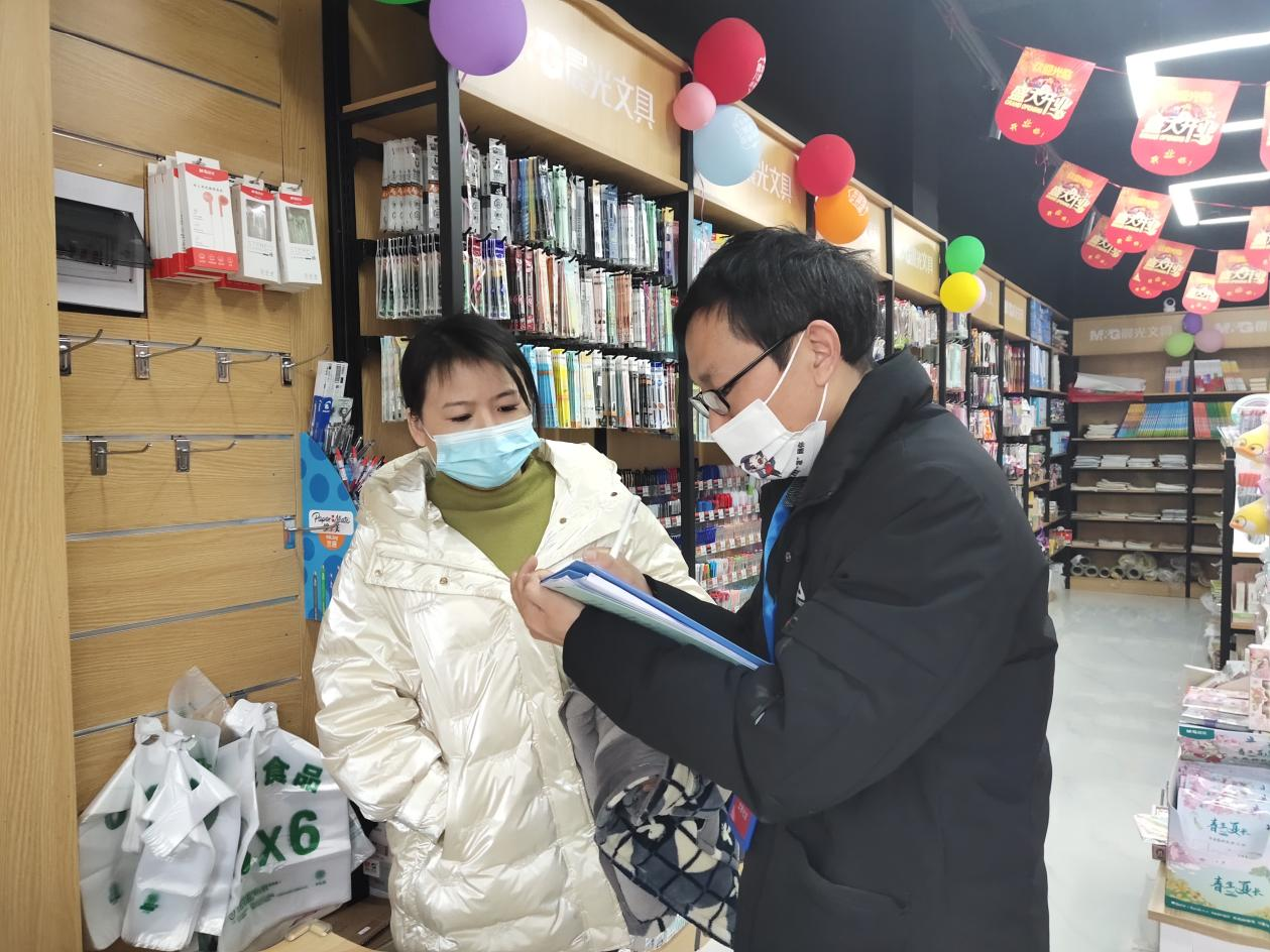 夏四美（右一）在社区走访门店，开展疫情防控工作。供图