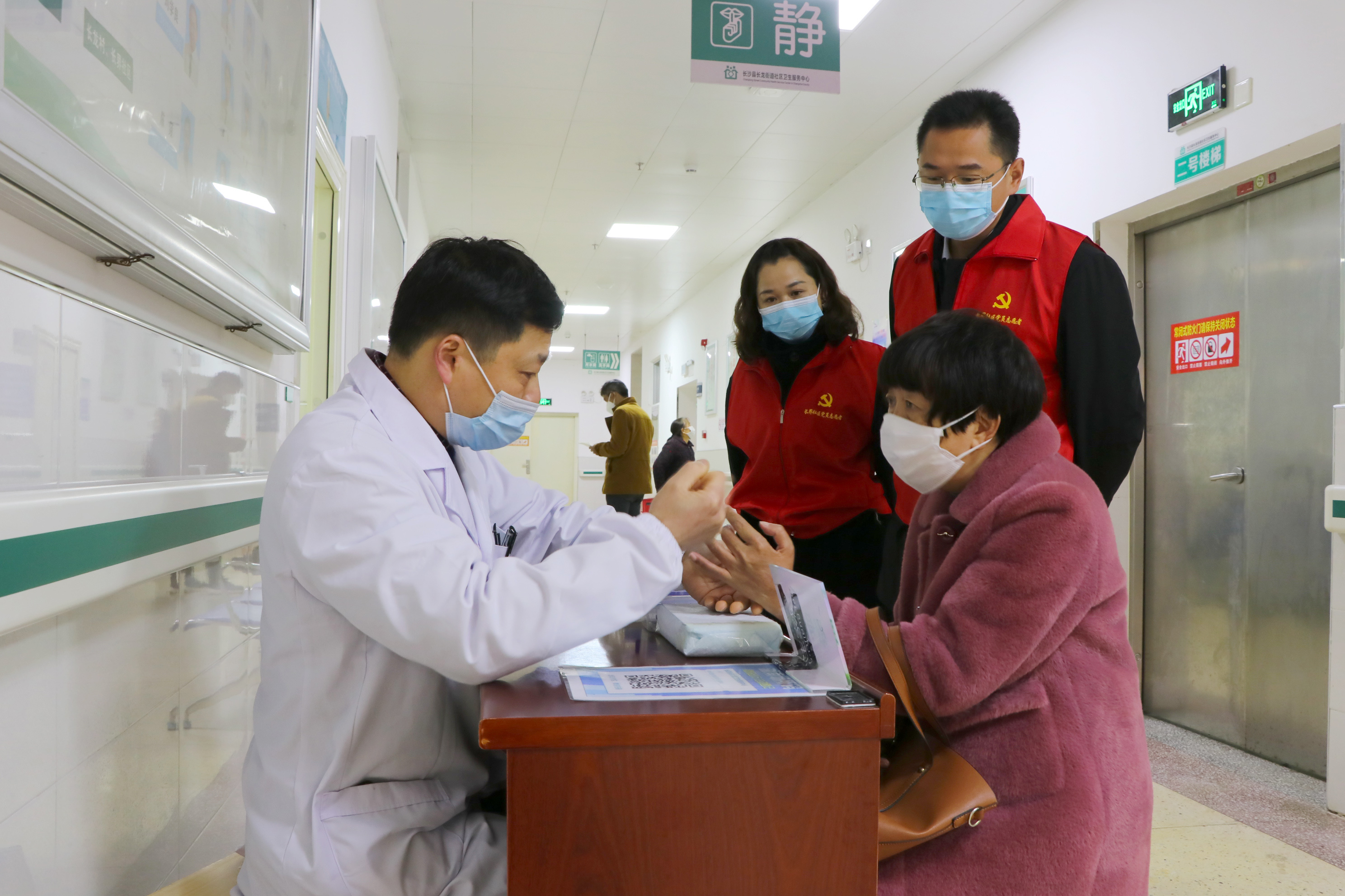 3月23日，在长龙街道社区卫生服务中心，陈鹏、隆干全程陪同单荣接做核酸检测。长沙晚报通讯员阮霖浩 摄