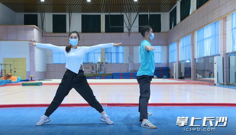 体育老师唐丽和周游录制室内舒缓操。