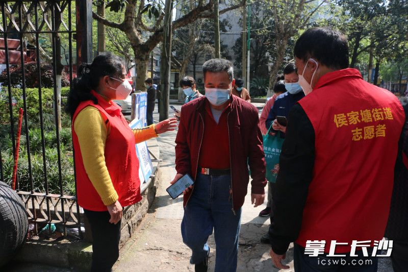 5名“红马甲”志愿者分成三道防线，负责扫场所码，提醒戴好口罩。
