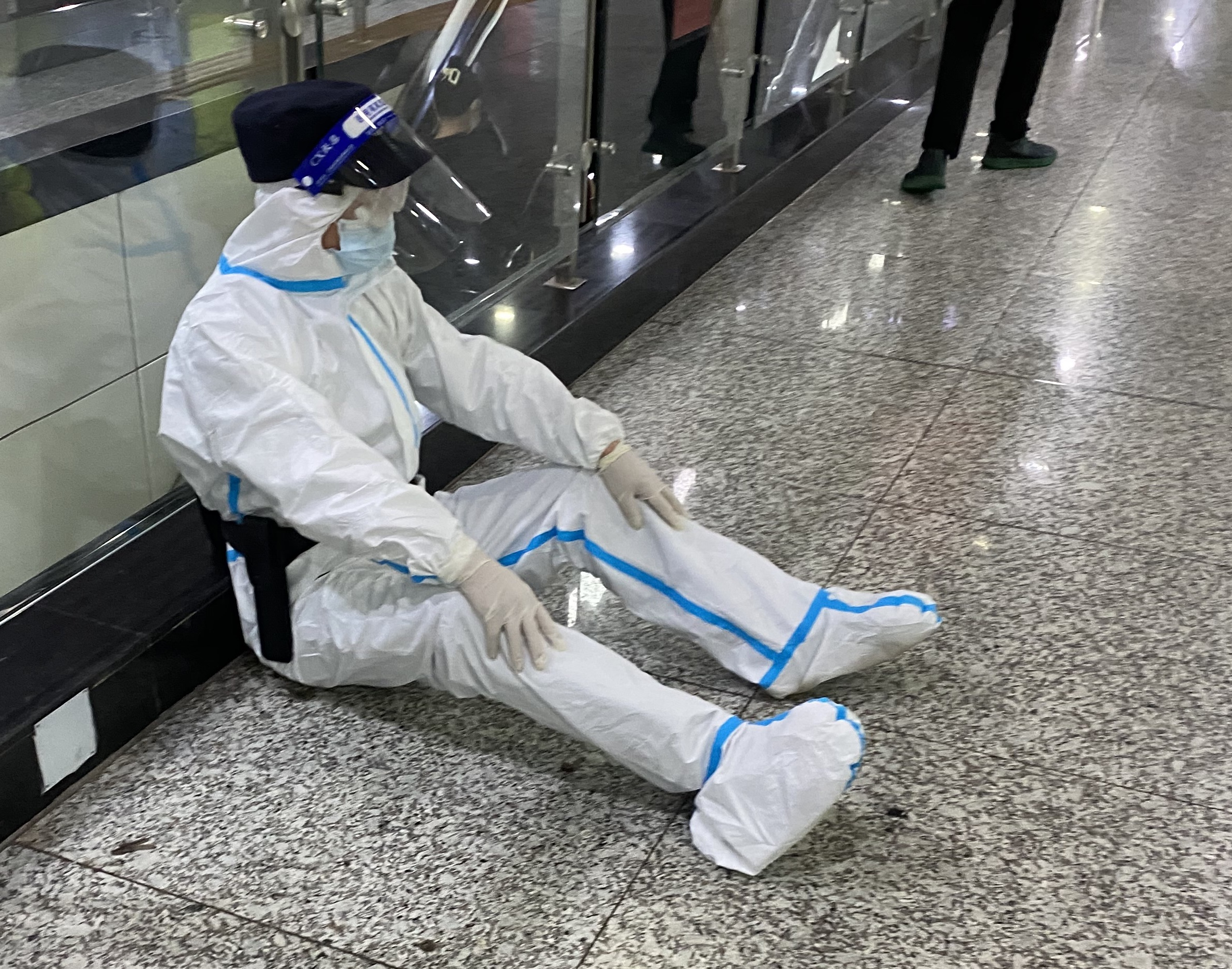53岁的许顺祥身穿防护服转运完健康码异常的乘客后，靠坐在地上休息。 长沙晚报通讯员 颜琼程 摄