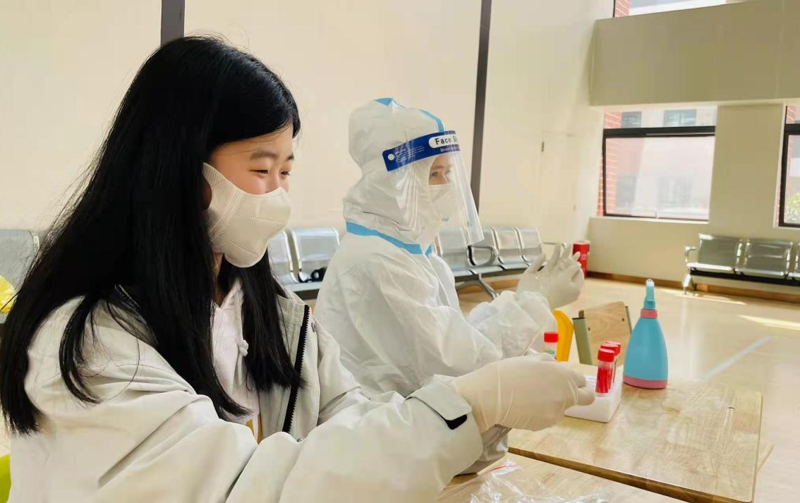 老师协助医护人员做核酸检测。