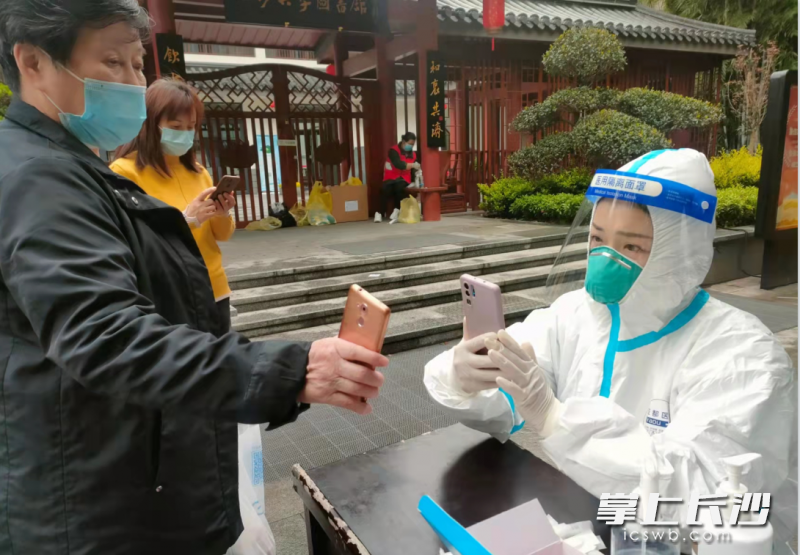 党员志愿者李格西正在白沙井检测点为前来核酸检测的居民扫码录入信息。