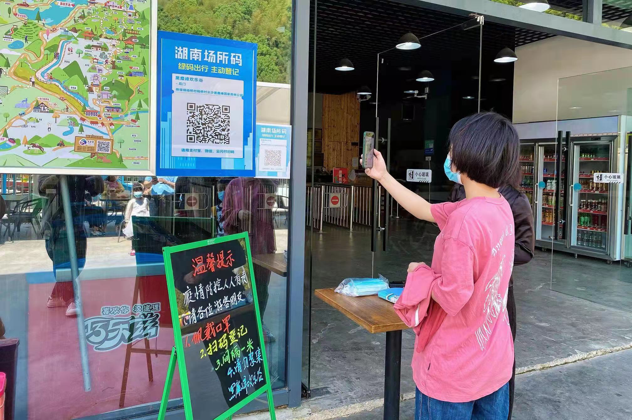 黑麋峰森林公园欢乐谷门前，一位游客正在扫场所码。