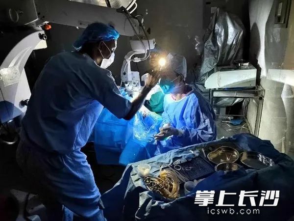 中国医疗队专家打着手电筒为塞拉利昂妇女Malmal做白内障手术。