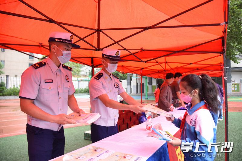消防救援人员现场向学生发放消防安全知识读本。