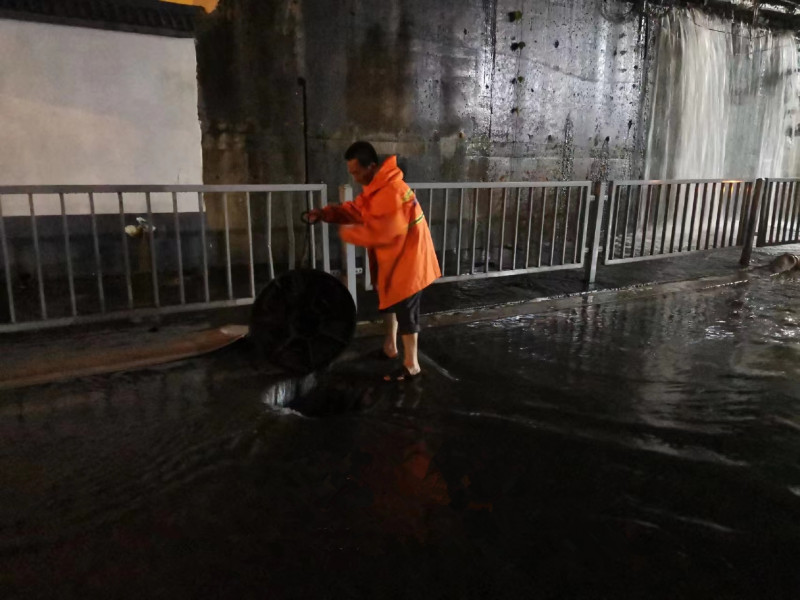 雨花市政工作人员打开下水井盖排水。