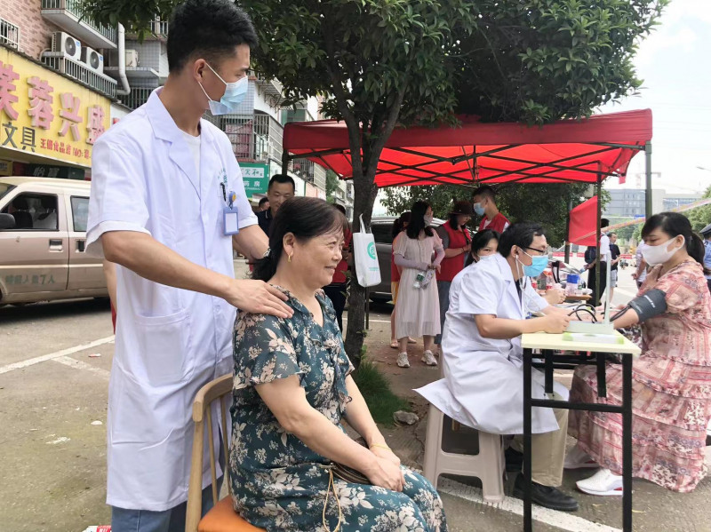 中医理疗师在为陪考家长提供免费肩颈放松按摩服务。