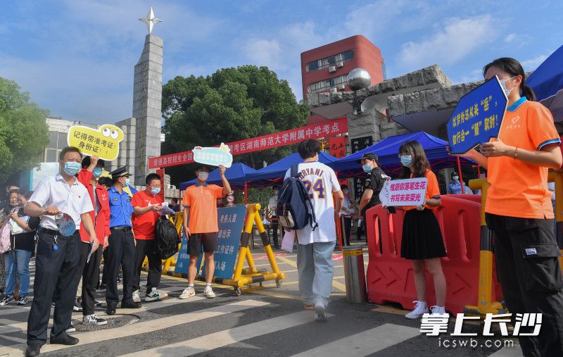 7日早上8时许，湖南师大附中考点，志愿者们举牌温馨提示考生不要忘带证件。 长沙晚报全媒体记者 邹麟 郭雨滴 摄