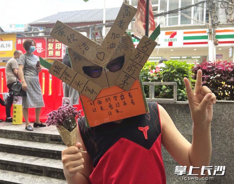 黄德文戴着自制的头盔在考场外等着姐姐出考场。长沙晚报全媒体记者 刘俊 摄